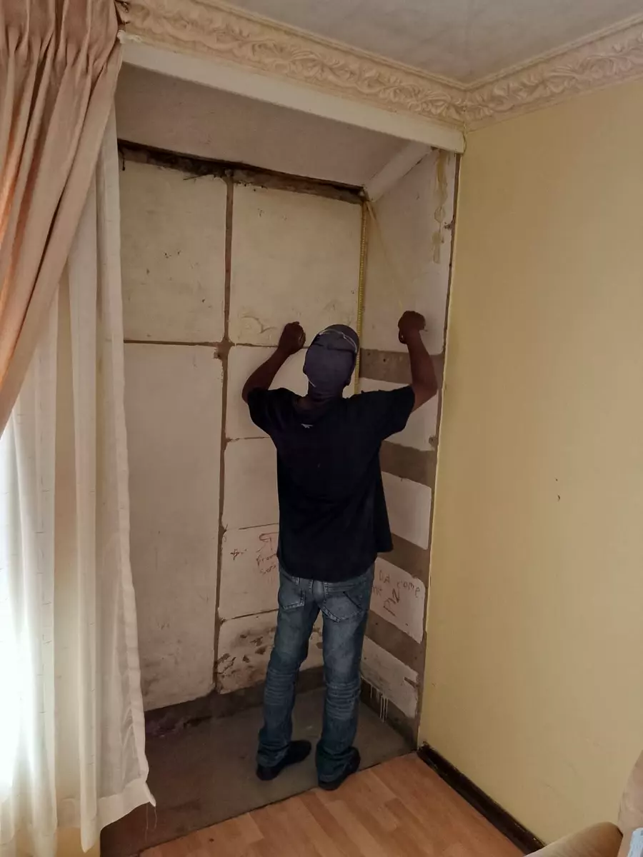 Man measuring built-in closet space with a tape measure