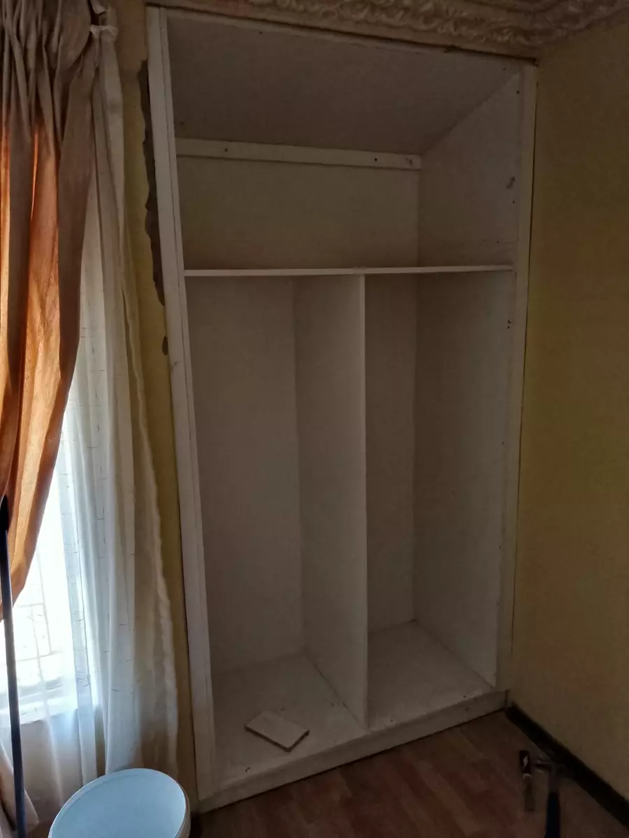 Unfinished built-in wardrobe unit with curtains on the left