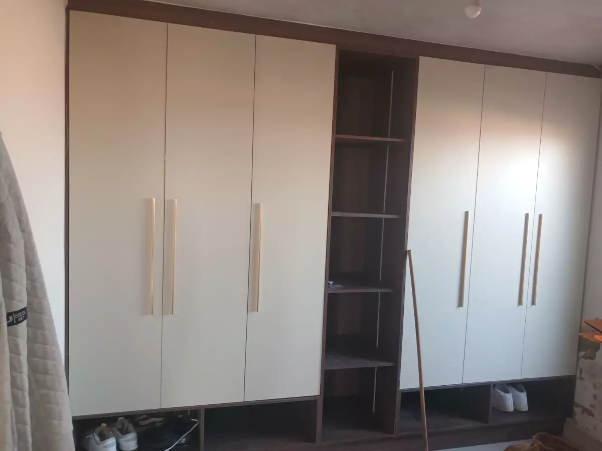 Large built-in fitted wardrobe with cream doors and open shelving