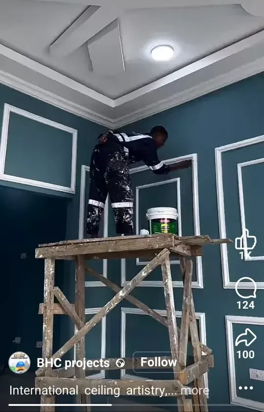 Painter on wooden scaffolding working on a teal wall with white wainscoting